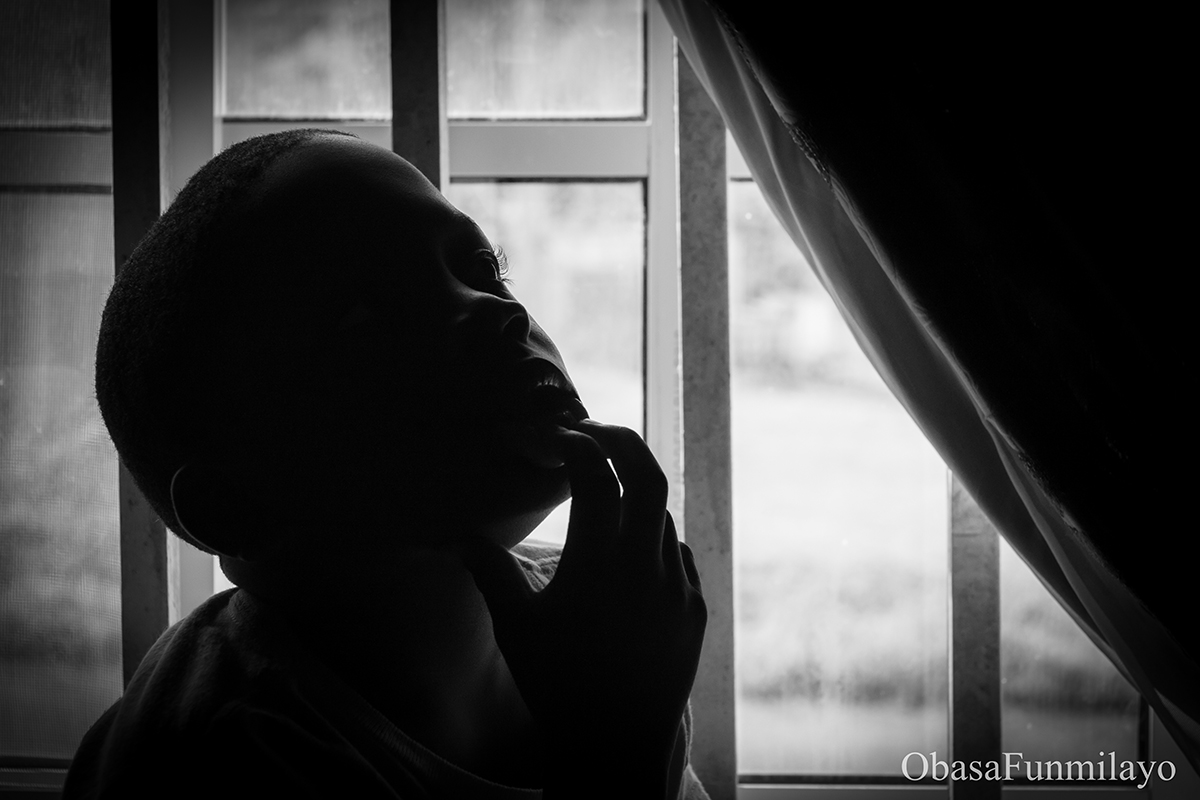 image of a boy silhouetted by light coming from the window-background